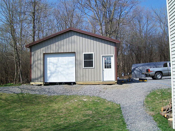 A pole barn with an overhead garage door, window and entry door.