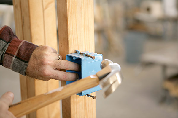 Hammering an electrical box to a post in a pole barn home