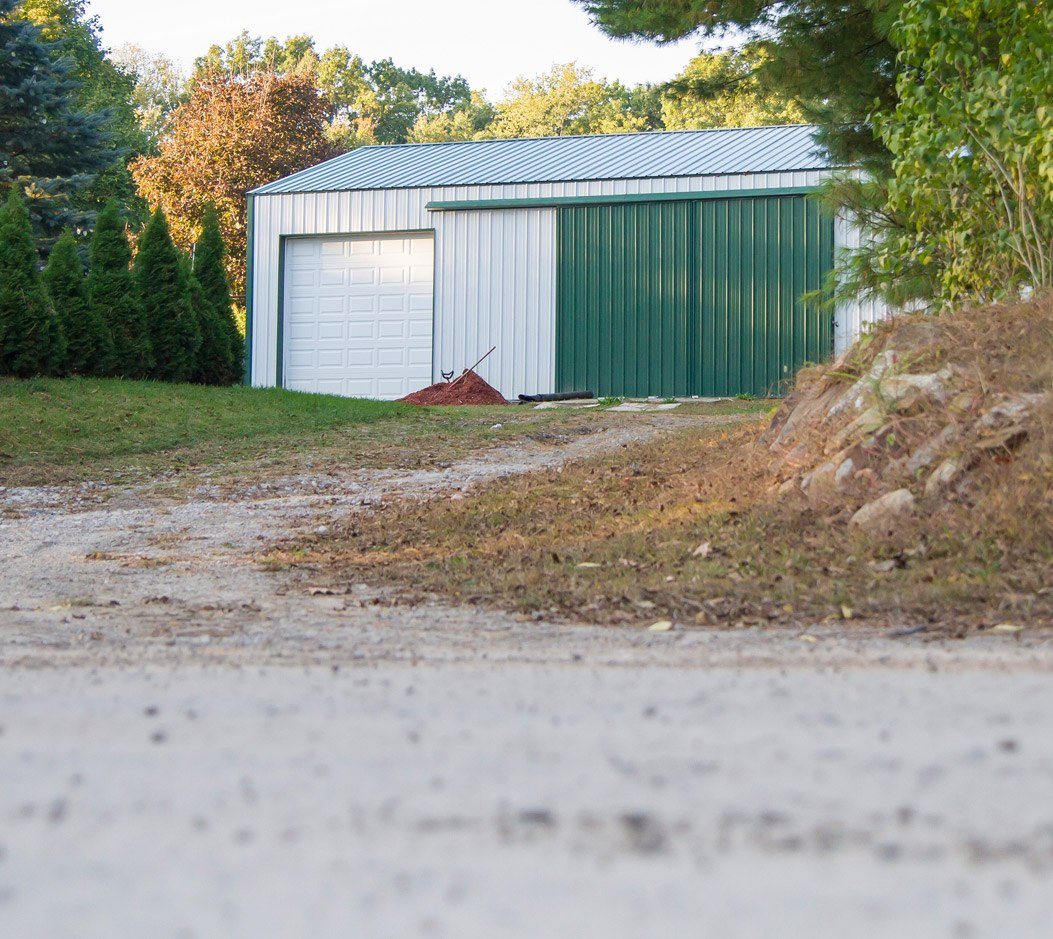 White pole barn with a large green door