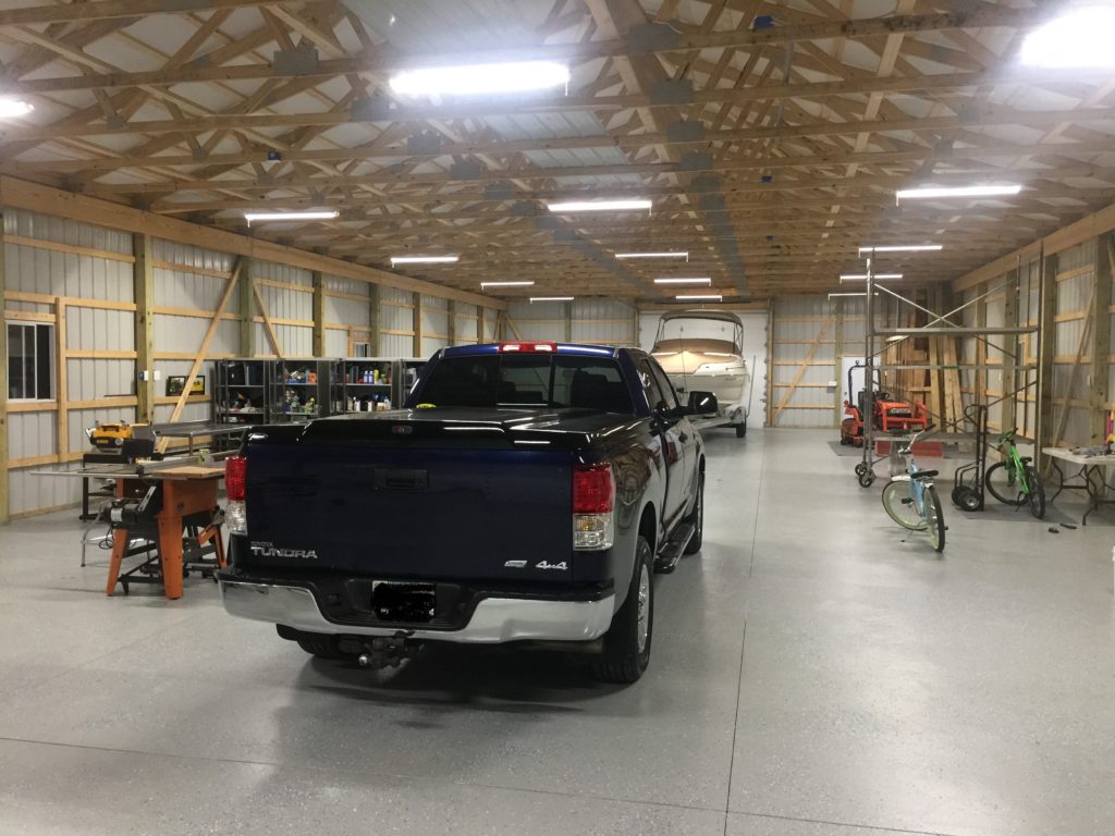 Large DIY pole barn garage storing a pickup truck, boat, bicycles and tools.