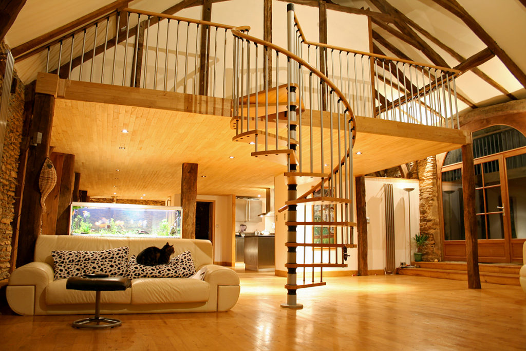 Pole barn living possibilities include a spiral staircase leading to a balcony overlooking a large open floor plan.