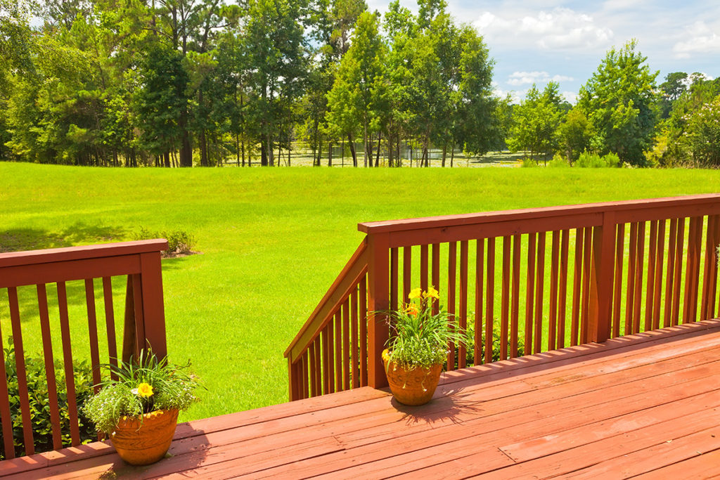 A beautiful lake view with trees is seen from this backyard deck. Considering the view is important when pole barn siting