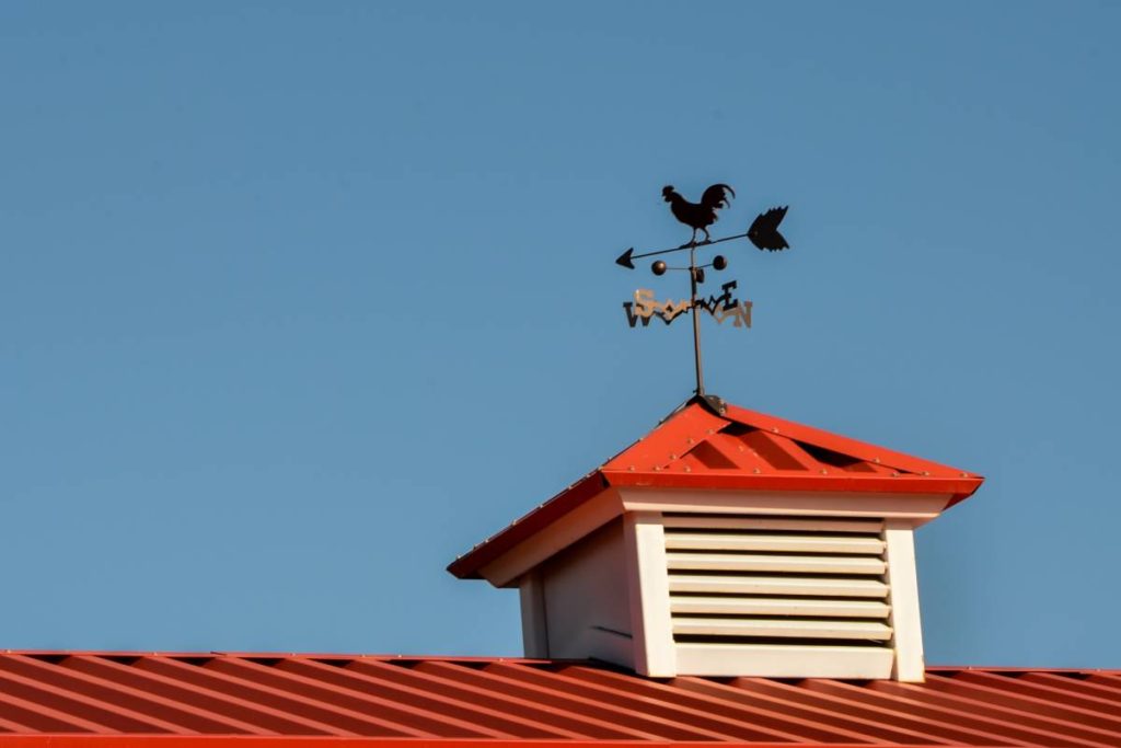 This red barn roof features a cupola-mounted weathervane. Learn more about pole barn cupolas with these top FAQ’s.