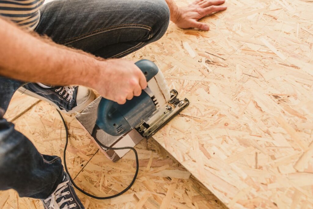 A builder cutting OSB panels for pole barn interior liner with a saw
